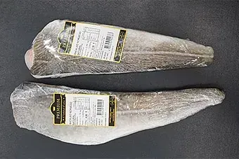 Dos trozos de pescado envueltos en plástico sobre una mesa.