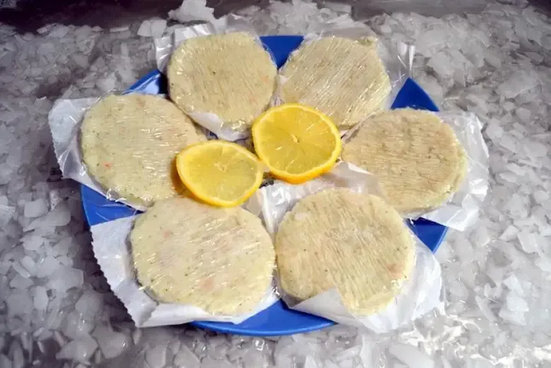 Un plato azul cubierto con hamburguesas y rodajas de limón.