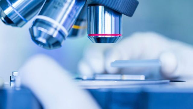 Una persona está mirando a través de un microscopio en un laboratorio.
