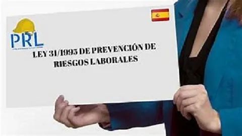 Una mujer con una chaqueta azul sostiene un cartel en español.