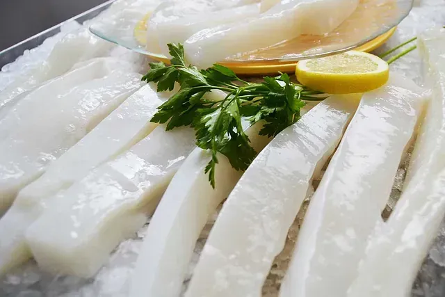 Un primer plano de un plato de pescado en hielo con una rodaja de limón y perejil.