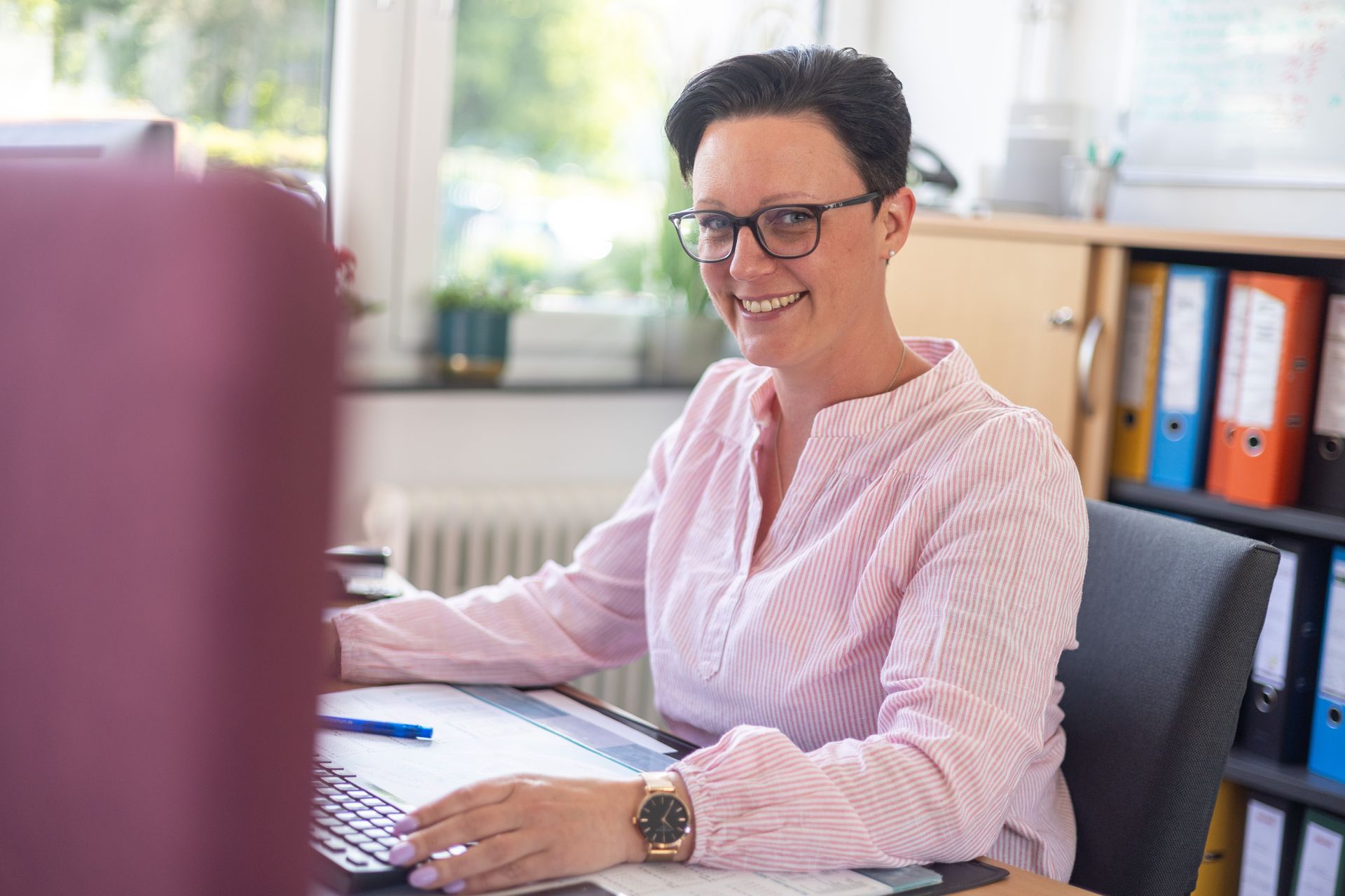 Eine Frau sitzt an einem Schreibtisch vor einem Computer.