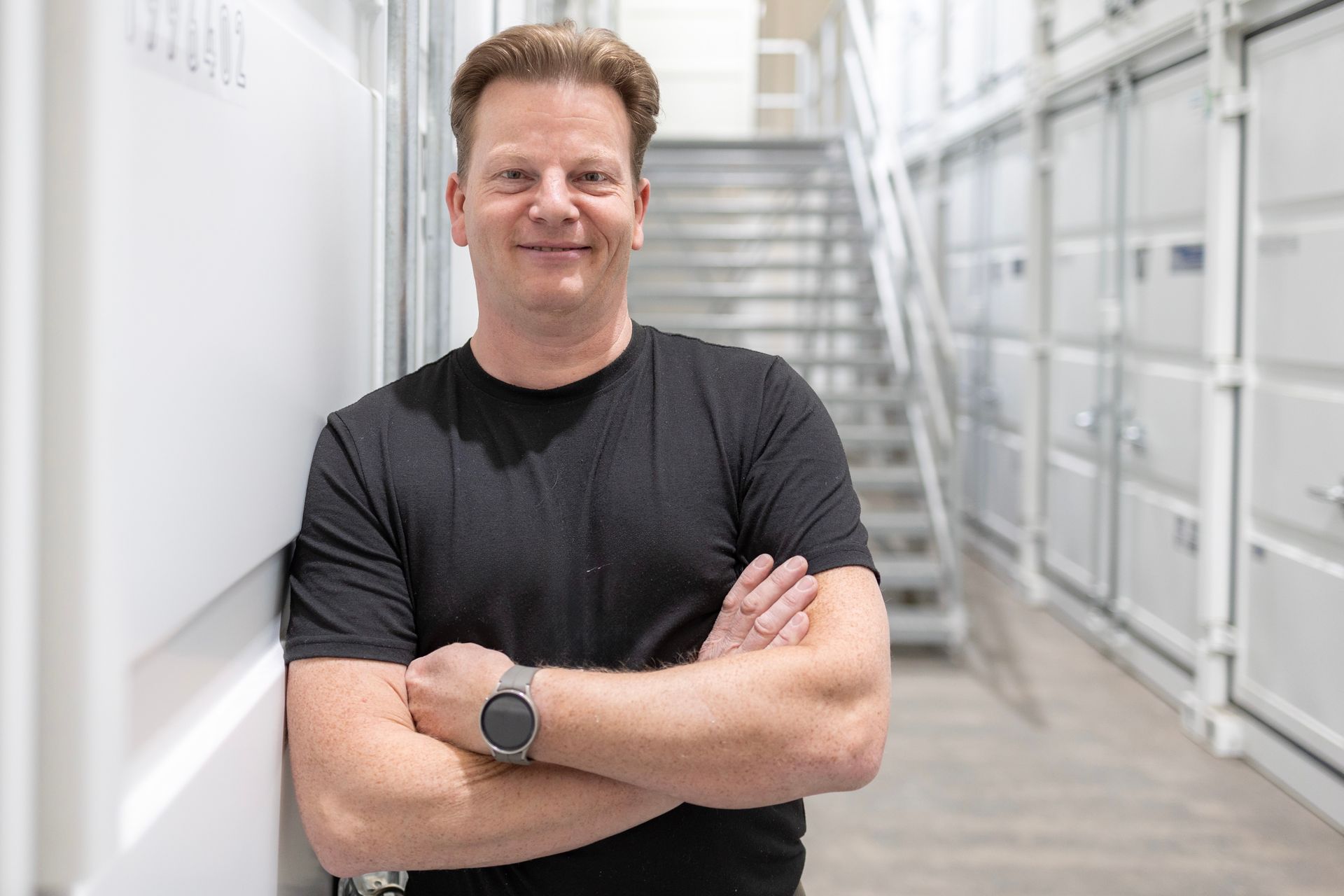 Ein Mann lehnt mit verschränkten Armen an einer Wand.