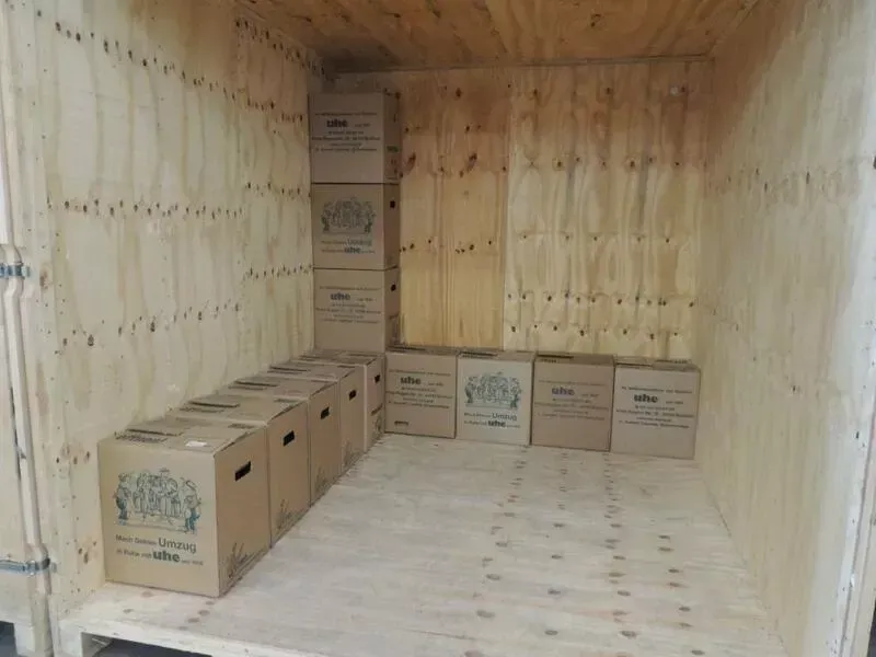 Eine Holzkiste voller Kartons auf einem Holzboden.