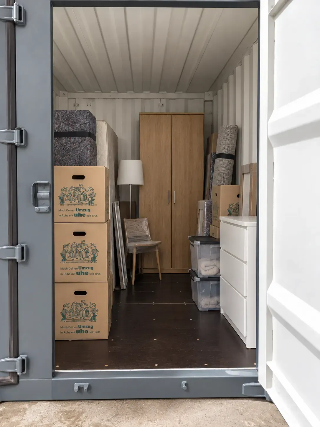 Eine mit Umzugskartons und Lagergut gefüllte Lagerbox aus Holz.