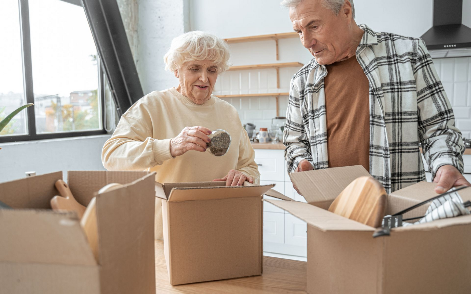 Zwei Personen packen Umzugskartons in einem hellen Raum
