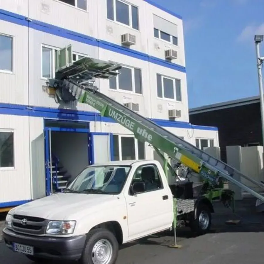 Ein weißer LKW mit einer an der Rückseite befestigten Leiter steht vor einem Gebäude