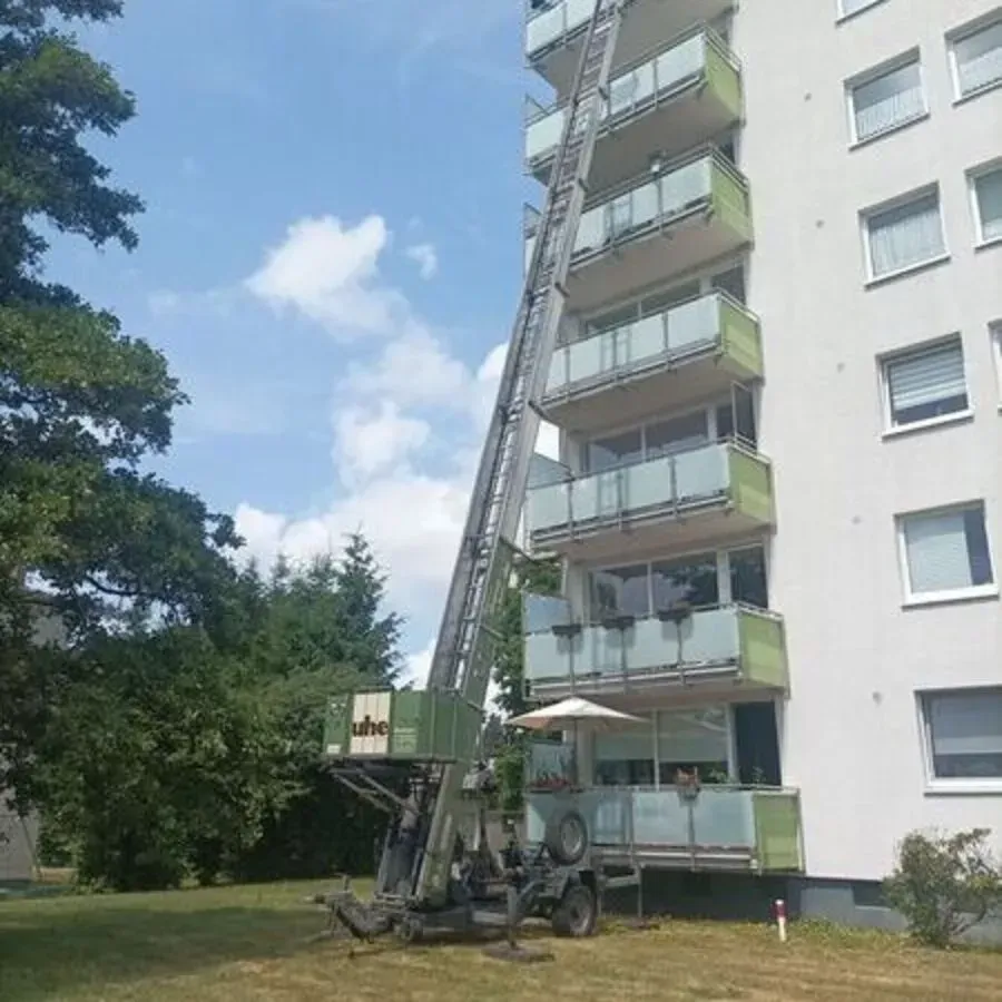 Vor einem hohen Gebäude steht eine Leiter.
