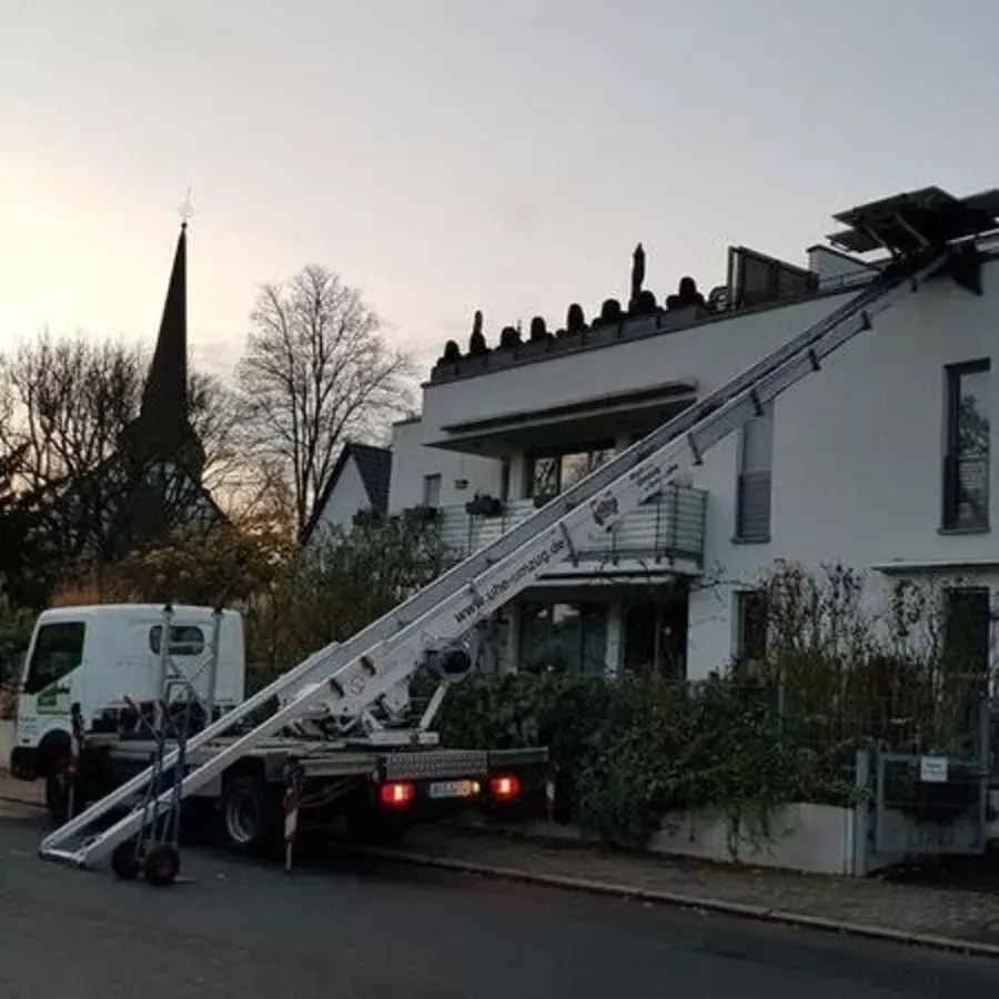 Vor einem Gebäude parkt ein Lastwagen mit einer daran befestigten Leiter.