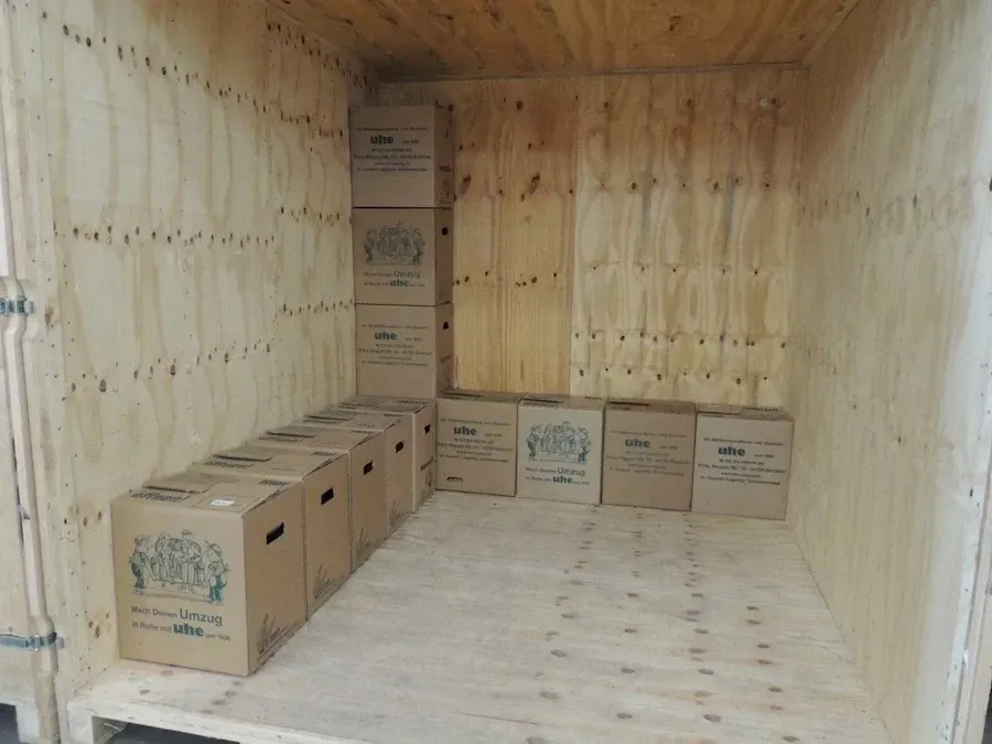 Eine Holzkiste voller Kartons auf einem Holzboden.