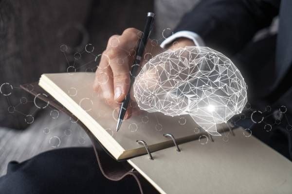 Escritura a mano en un cuaderno con un icono de cerebro digital brillante superpuesto.
