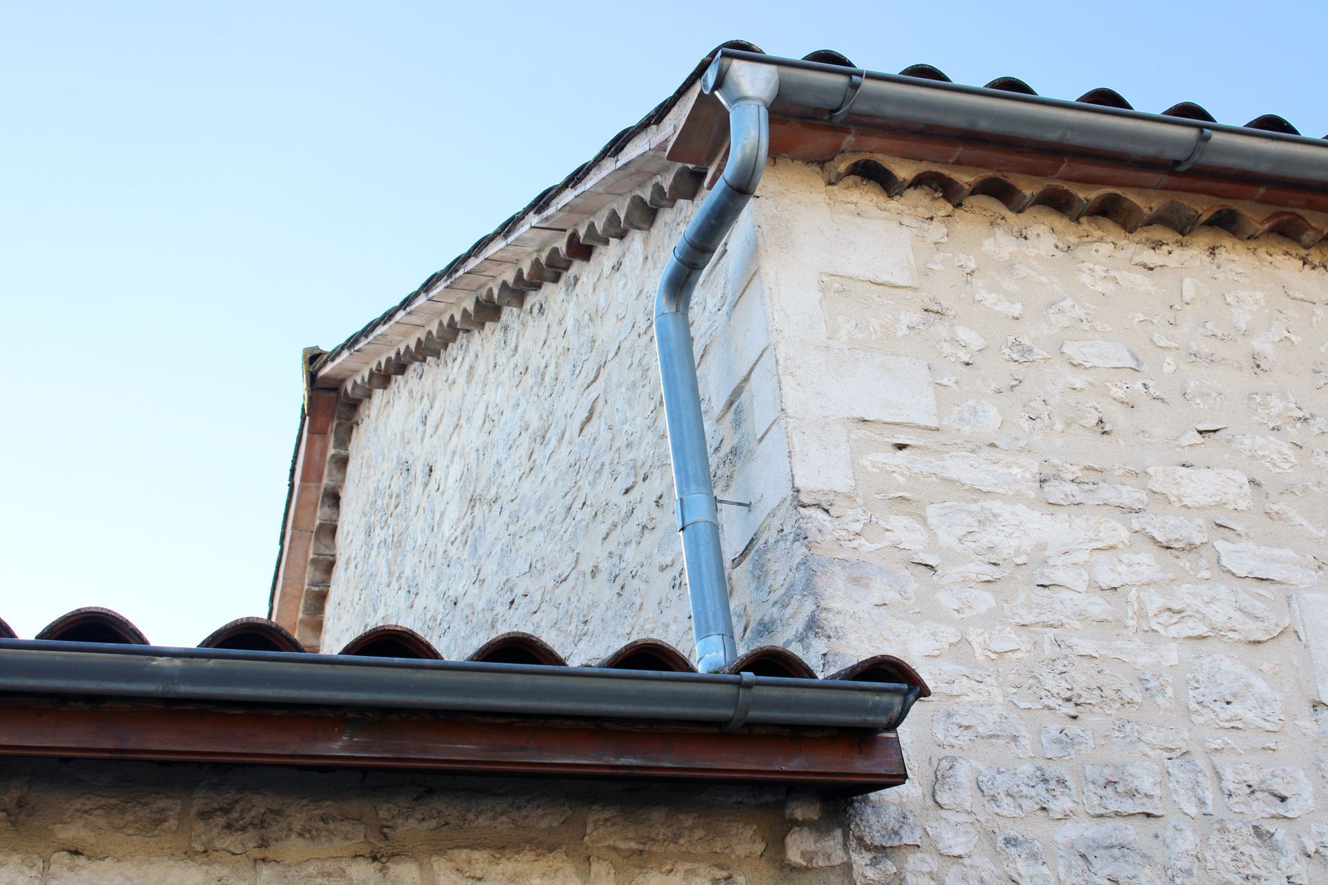 Gouttière et descente de gouttière accrochées au mur d'une maison.