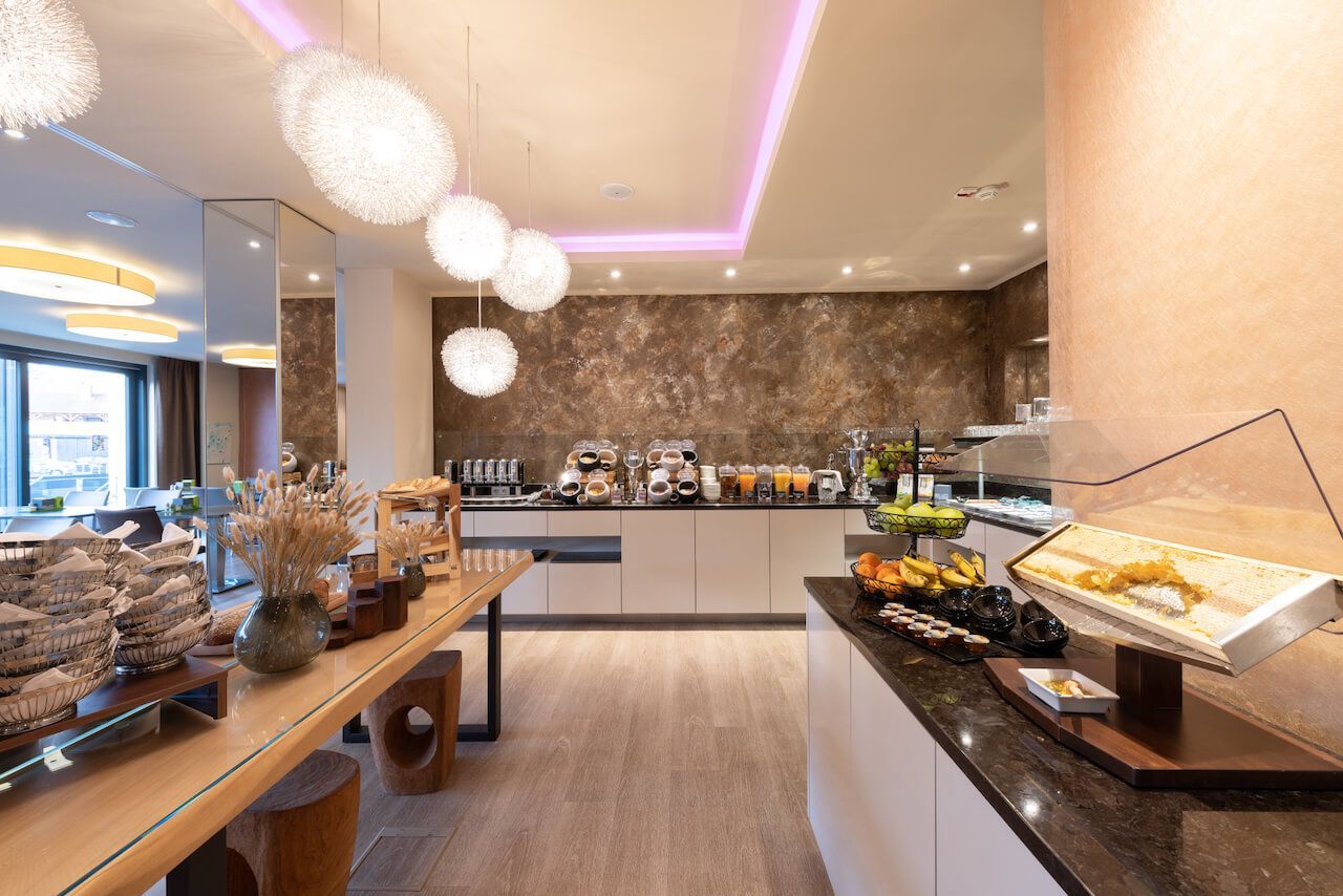 Modernes Hotel-Frühstücksbuffet mit Gebäck, Obst und Pendelleuchten in einem hellen Speisesaal in Kirchheimbolanden.