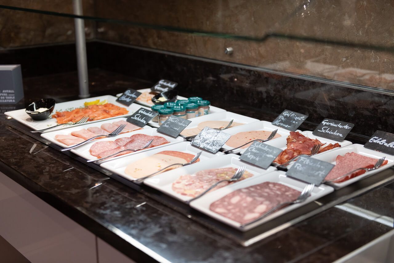 Eine Auswahl an rohem Fleisch und Meeresfrüchten wird auf Eis in einer Kühltheke mit kleinen Etiketten präsentiert.