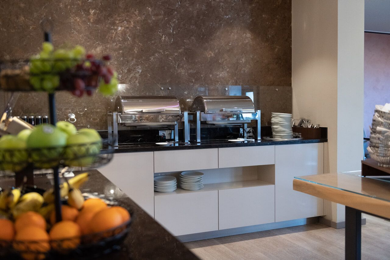 Buffettheke mit Tabletts, Tellern, Obst und Gebäck in einem modernen Essbereich