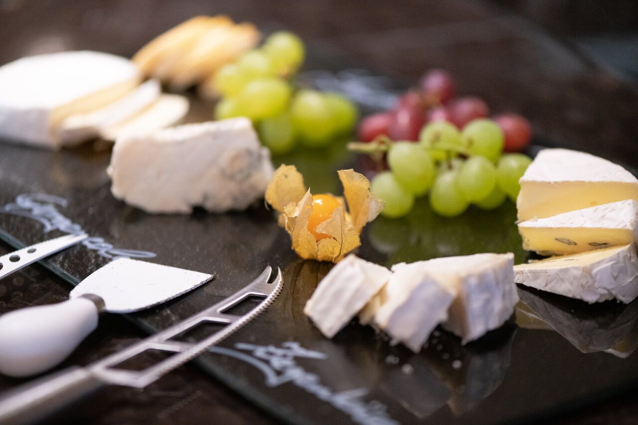 Käse und Weintrauben auf einem Schieferbrett mit Crackern und Besteck angerichtet zum Frühstück in Kibo.