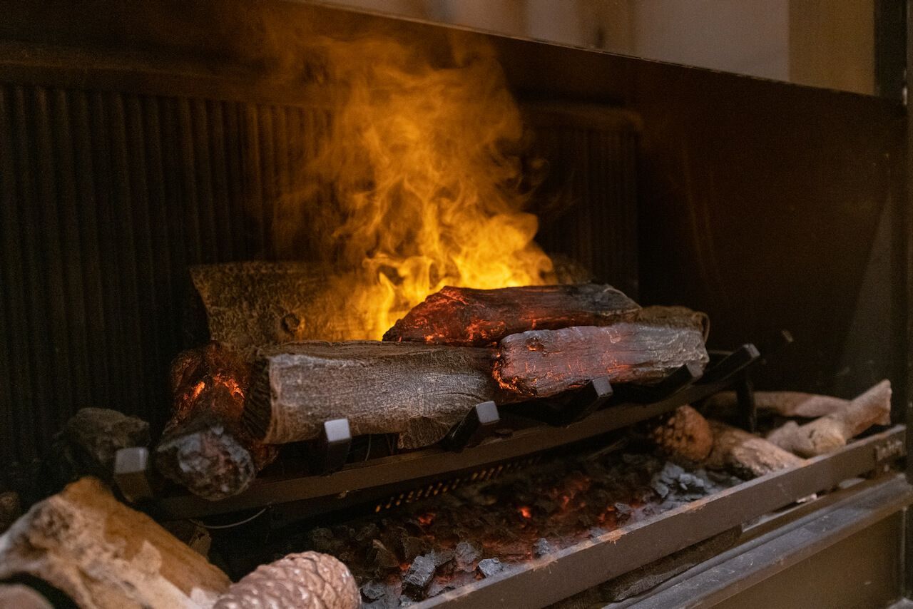 Brennende Holzscheite in einem Kamin mit hellorangefarbenen Flammen und glühenden Glutstücken im Ruheraum im SPA.