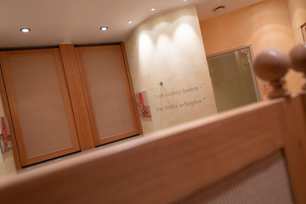 Gemütlicher SPA mit holzgetäfelten Wänden, Einbauleuchten und einer Schwingtür im Vordergrund im SPA.