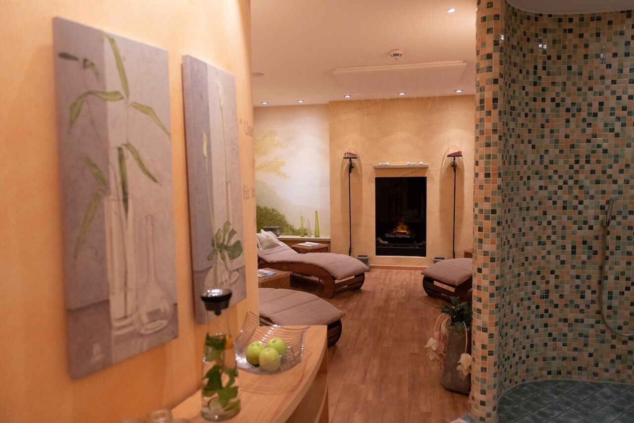 Spa-Ruheraum mit Massageliegen, warmem Licht, Holzböden und einer Mosaikfliesenwand im SPA bei Alzey.