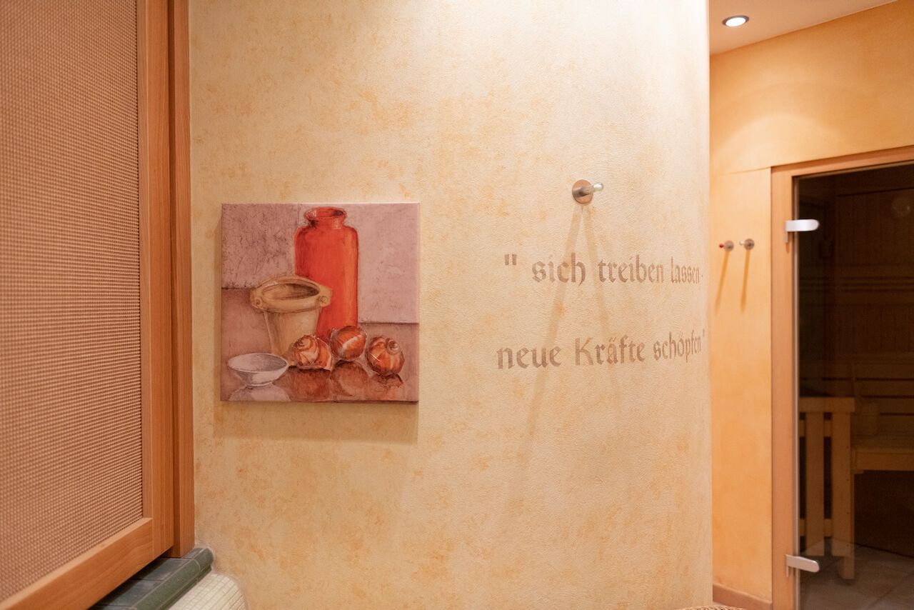 Warmer beigefarbener Flur mit einem kleinen roten Vasenbild und dekorativer Wandbeschriftung in der Nähe einer Tür im Spa.