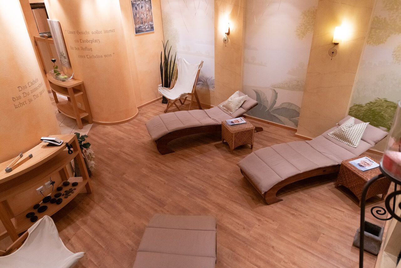 Gemütliche Spa-Lounge mit geschwungenen Liegen, warmer Beleuchtung, Holzboden und Topfpflanzen im Saunabereich.
