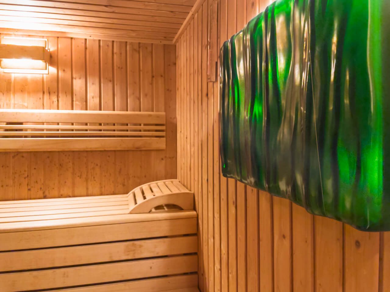 Saunainterieur aus Holz mit Bänken und leuchtend grünen Wandpaneelen im SPA.