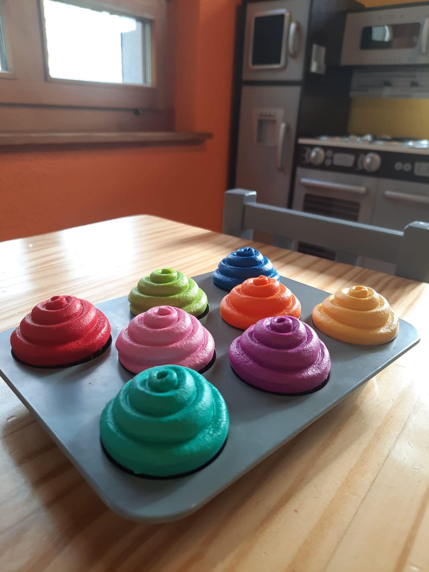 Ein Tablett mit bunten Cupcakes auf einem Holztisch