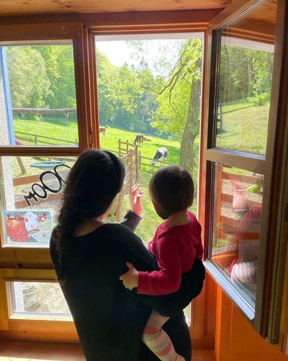 Eine Frau hält ein Kind und schaut aus einem Fenster.