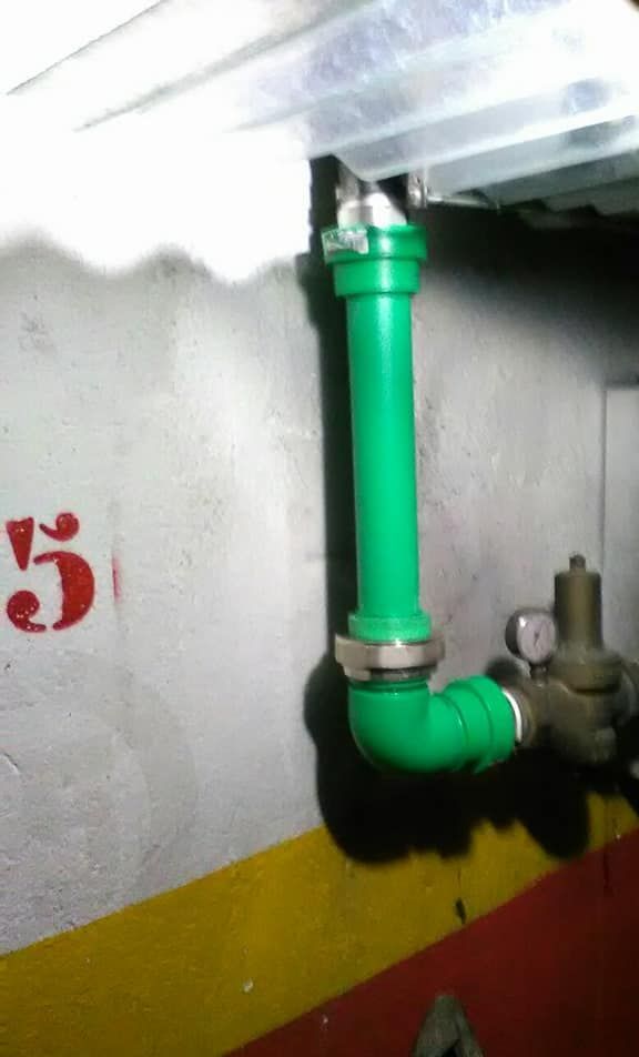 Una tubería verde está fijada a una pared con el número 5 pintado en ella.