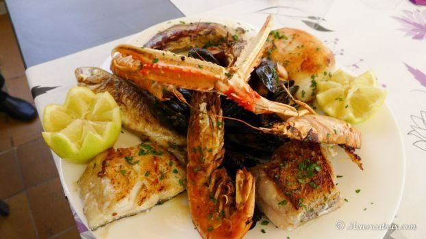 Un plato de ostras en hielo junto a una taza de sopa en una mesa.