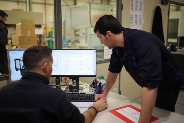 Dos hombres miran una pantalla de computadora en una oficina.