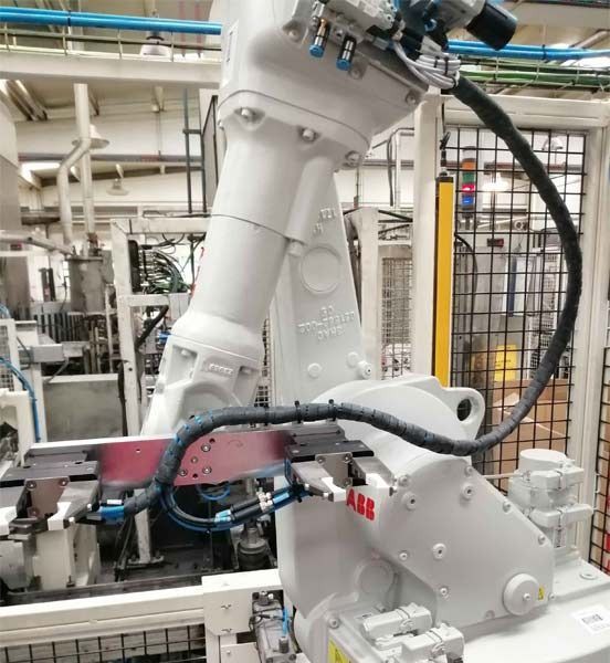 Un brazo robótico blanco está sentado en una fábrica.