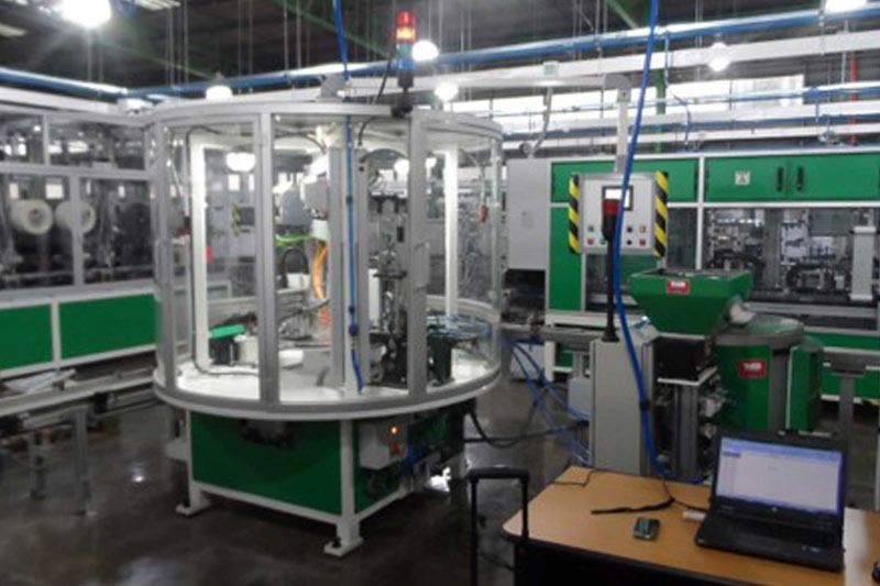 Una computadora portátil está sobre una mesa frente a una máquina en una fábrica.