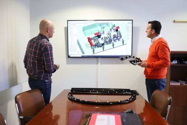 Dos hombres miran una pantalla de computadora en una sala de conferencias.