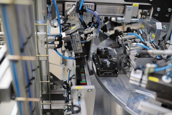 Un primer plano de una máquina en una fábrica con muchos cables saliendo de ella.