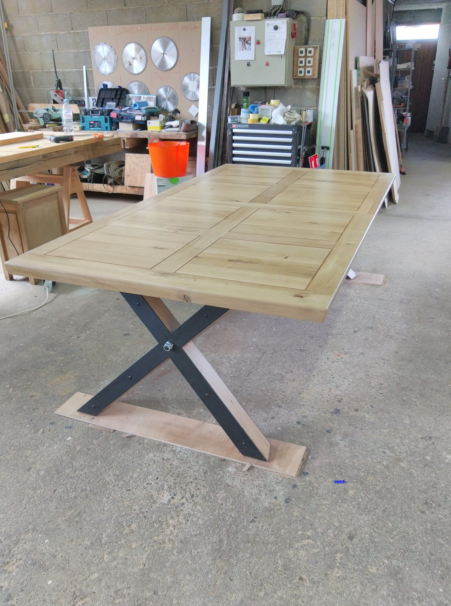 Table pliante en bois avec pieds métalliques en forme de X dans un atelier