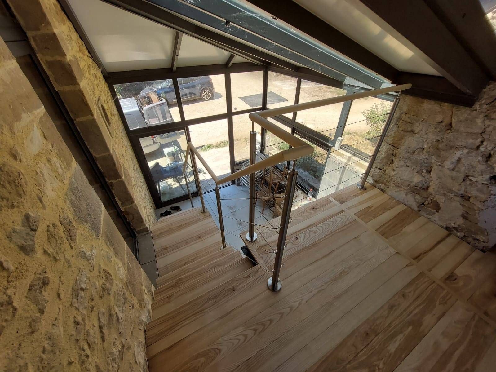 Escalier en pierre avec rampe en verre et puits de lumière dans un intérieur rustique