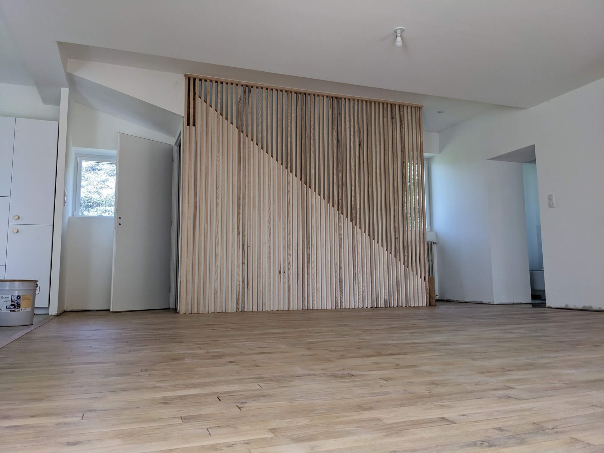 Pièce moderne vide avec parquet et mur à lattes verticales.