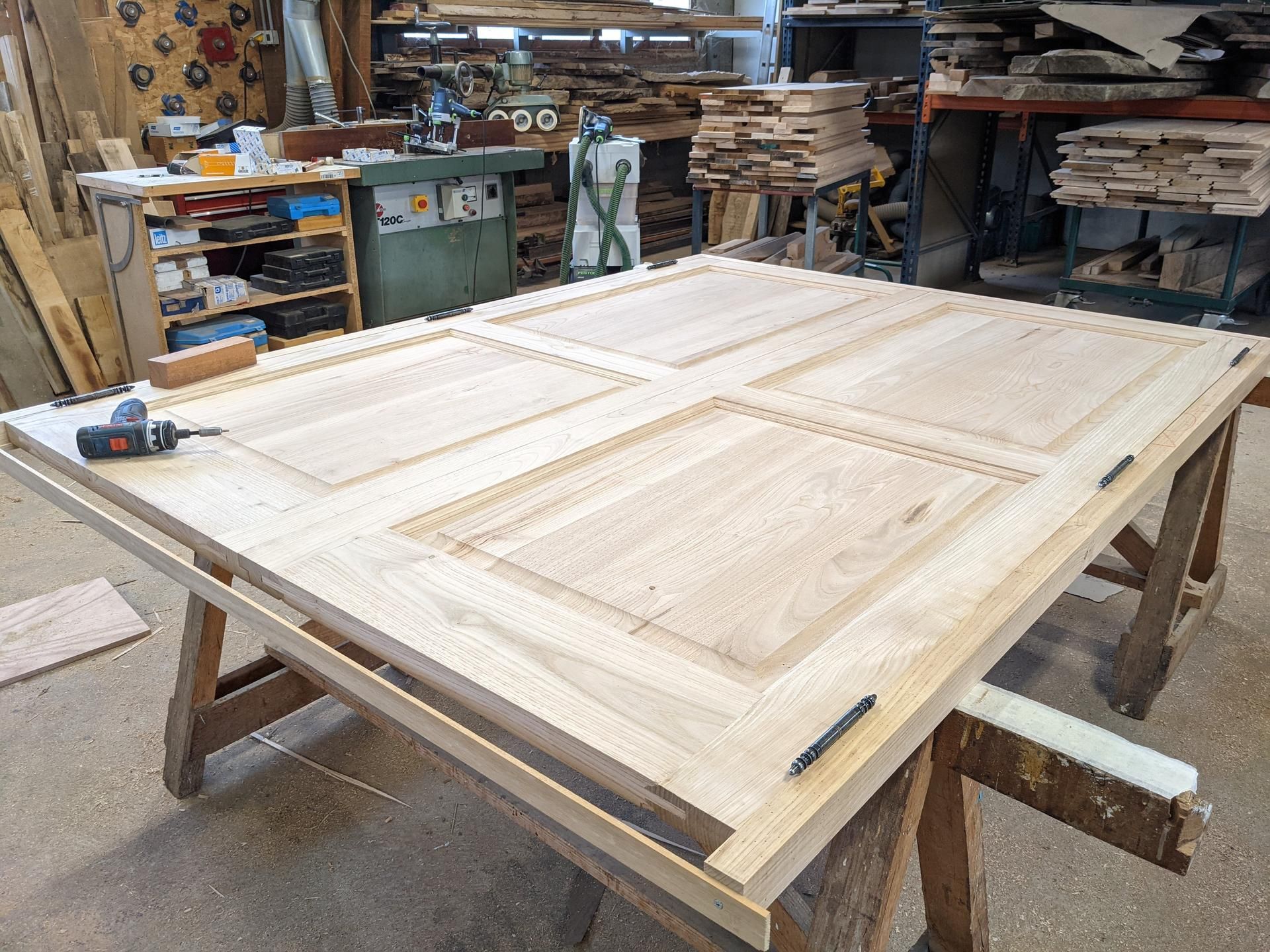 Grand panneau de porte d'armoire en bois brut sur un établi dans un atelier de menuiserie