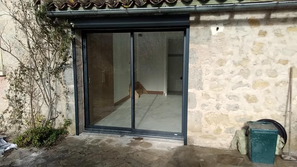 Terrasse en pierre avec de grandes portes coulissantes en verre et un seau vert près du mur