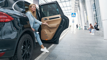 Une femme descend d'un SUV noir dans une zone de dépose minute d'aéroport