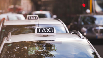 Filet de taxis blancs dans une rue de la ville, avec circulation et lumières floues en arrière-plan.
