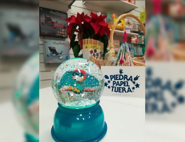 Una bola de nieve está sobre una mesa frente a un cartel que dice piedra papel tuera