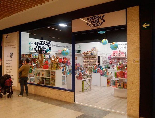 Un hombre empuja un cochecito frente a una juguetería.