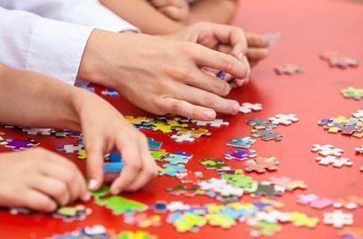 Un grupo de personas está jugando un rompecabezas en una mesa roja.