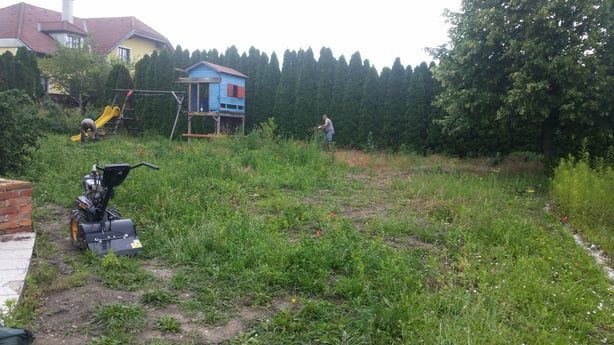 Eine Person kümmert sich um einen verwilderten Garten; eine Gartenfräse und ein Spielplatz sind zu sehen.