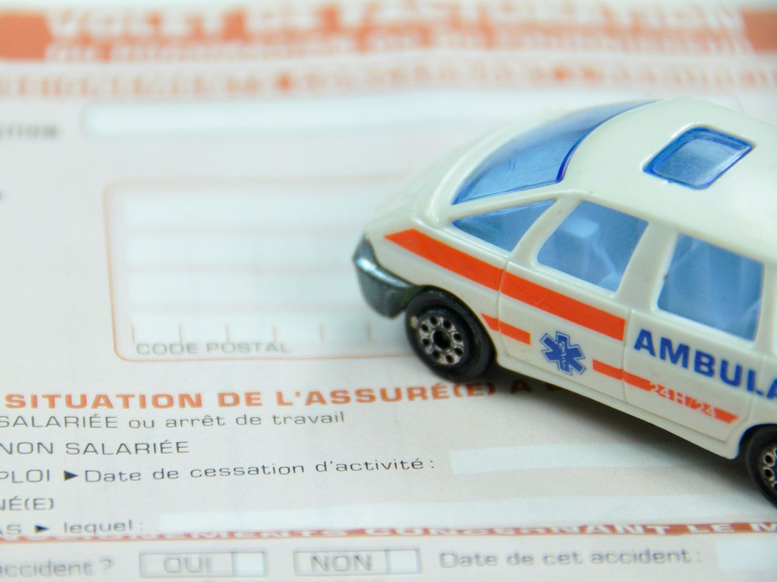 Figurine d'ambulance posée sur un papier de la CPAM