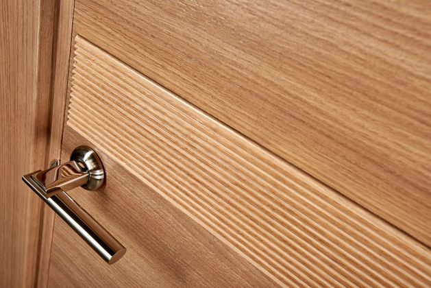 Gros plan sur une porte d'intérieur en bois, avec une poignée argentée.