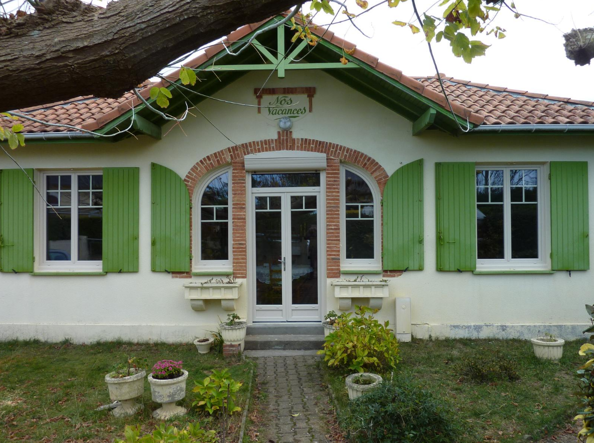 La façade d'une maison aux menuiseries vertes.