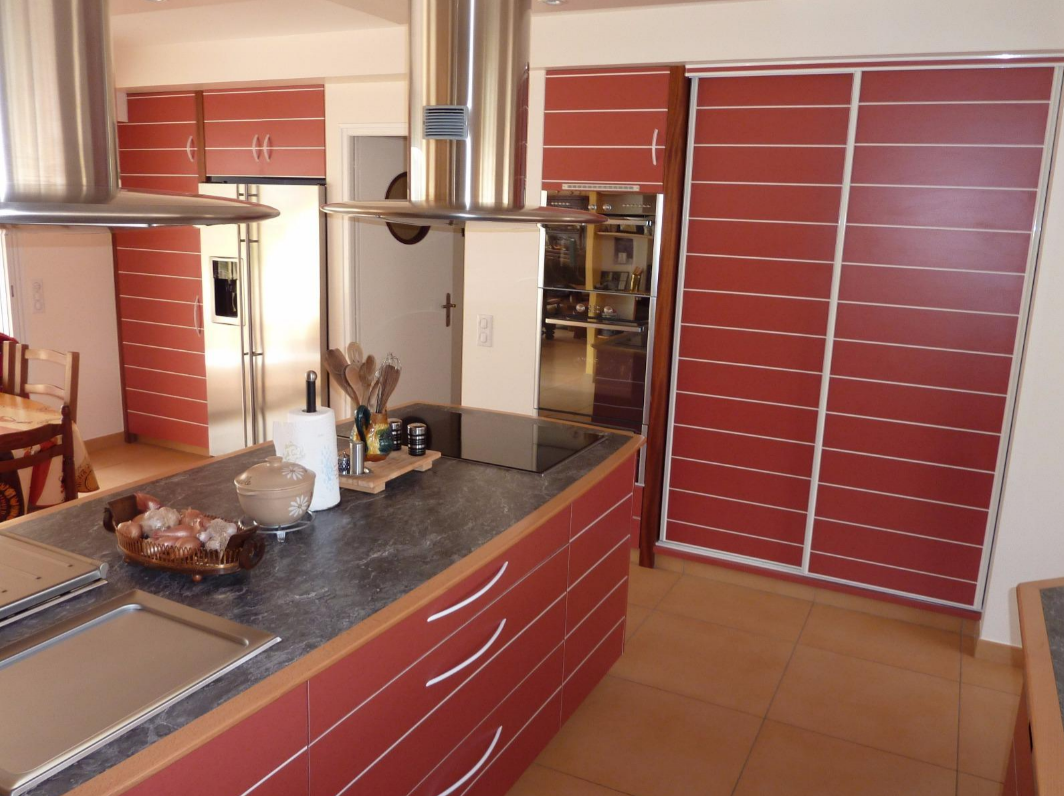 Cuisine moderne avec des placards rouges et un plan de travail noir marbré.